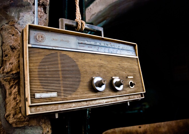 A0272 - Älterer, brauener Radio hängt an einem Strick vor einer Wand